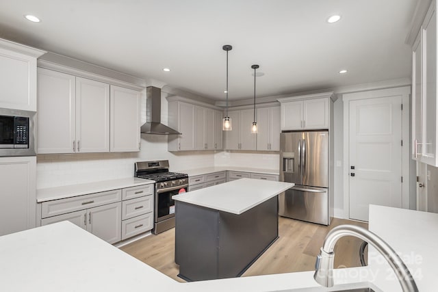 kitchen with pendant lighting, light hardwood / wood-style flooring, wall chimney range hood, stainless steel appliances, and decorative backsplash