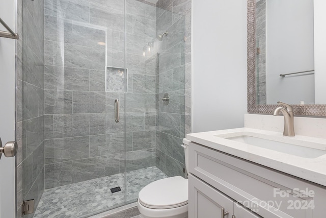 bathroom featuring a shower with shower door, vanity, and toilet