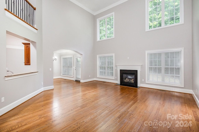 unfurnished living room featuring ornamental molding, a high ceiling, light hardwood / wood-style floors, and a premium fireplace