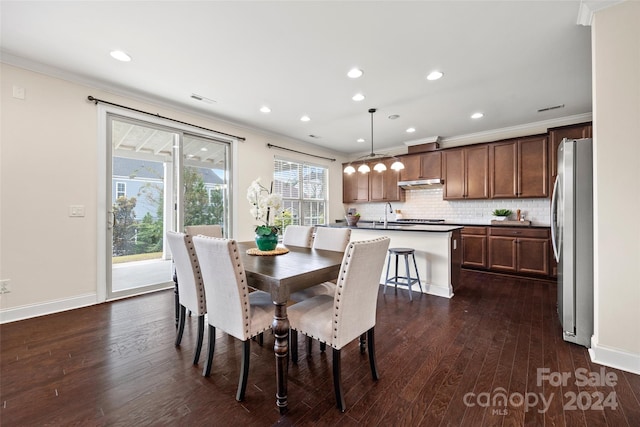 dining space with dark hardwood / wood-style floors, sink, and crown molding