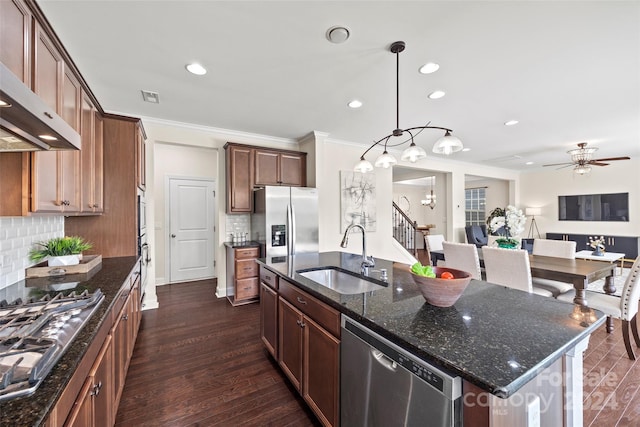 kitchen with dark wood-type flooring, sink, an island with sink, stainless steel appliances, and decorative light fixtures