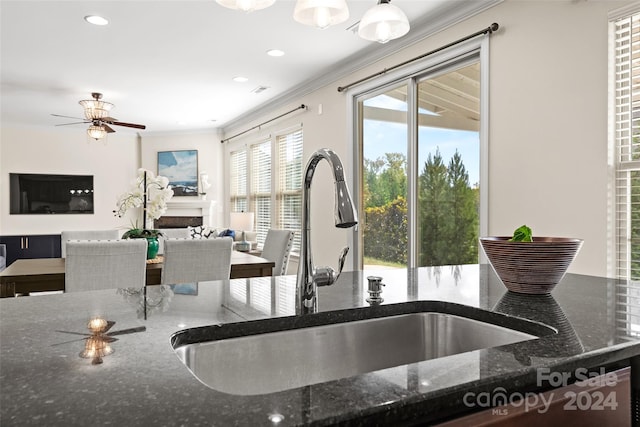 kitchen with crown molding, dark stone countertops, sink, and ceiling fan