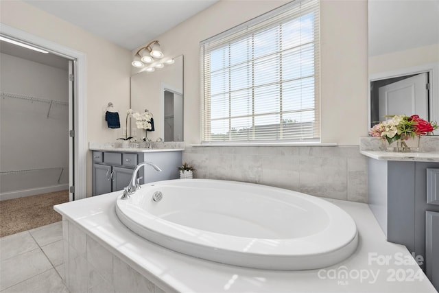 bathroom featuring tile patterned flooring, vanity, and a relaxing tiled tub