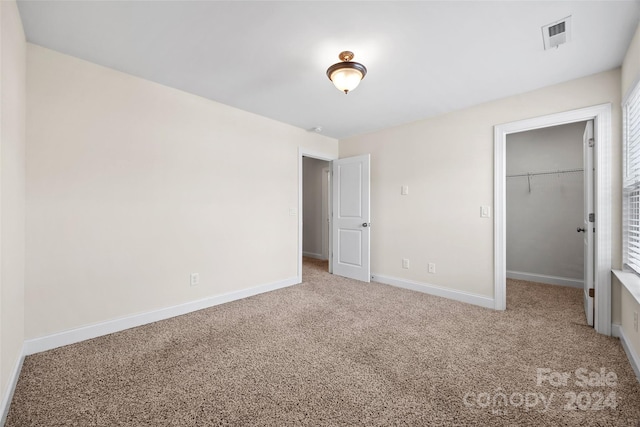 unfurnished bedroom featuring carpet floors, a walk in closet, and a closet