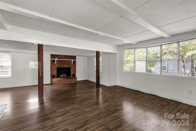 unfurnished living room with a healthy amount of sunlight, beamed ceiling, dark hardwood / wood-style floors, and a fireplace