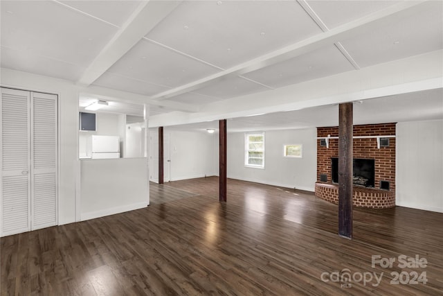 basement featuring a brick fireplace, white refrigerator, and dark hardwood / wood-style flooring