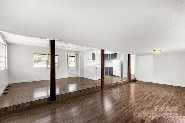 unfurnished living room with ornate columns, a textured ceiling, and dark hardwood / wood-style flooring