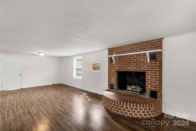 unfurnished living room with a brick fireplace, a textured ceiling, and hardwood / wood-style floors