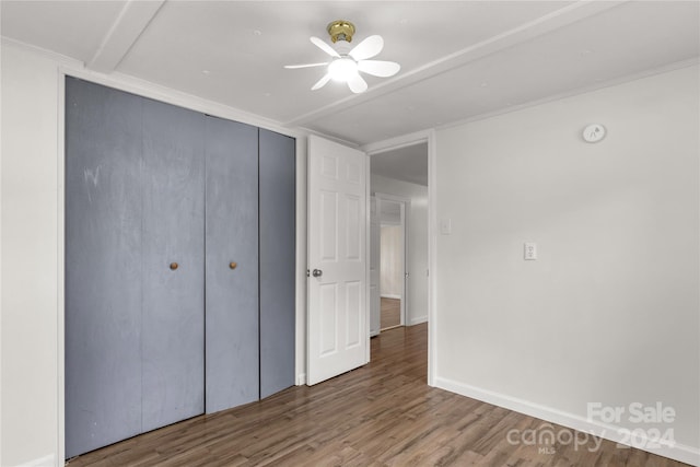 unfurnished bedroom featuring a closet, wood-type flooring, ceiling fan, and ornamental molding