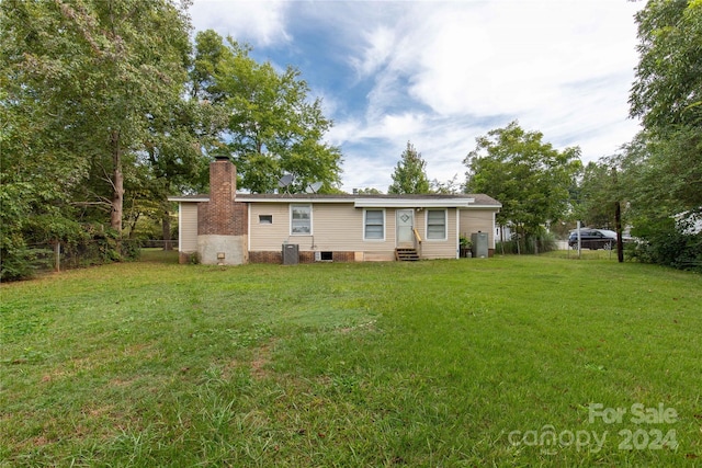 back of house with cooling unit and a yard