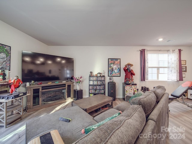 living room with light hardwood / wood-style floors, a fireplace, and vaulted ceiling