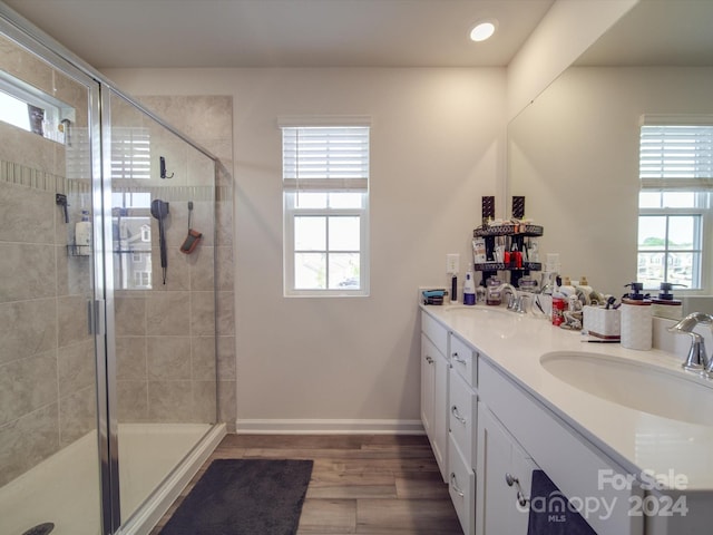 bathroom featuring a healthy amount of sunlight, vanity, hardwood / wood-style floors, and a shower with shower door