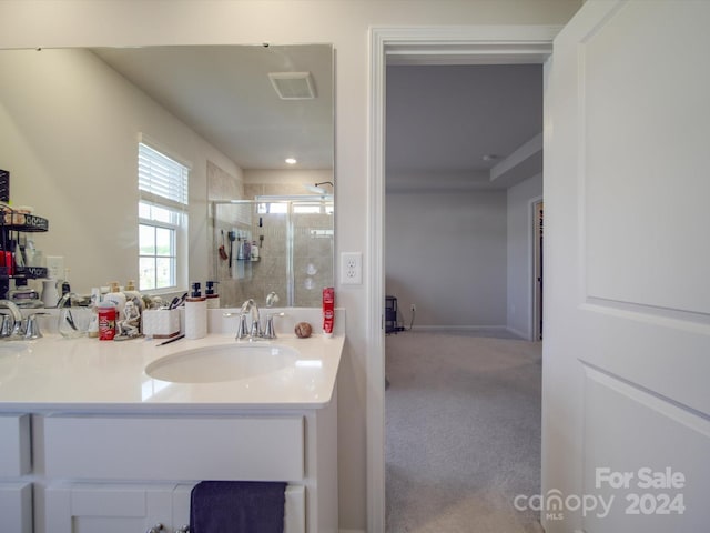 bathroom featuring a shower with door and vanity