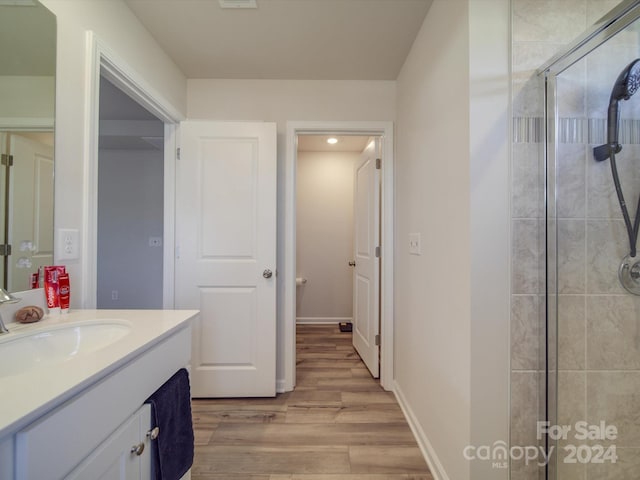 bathroom with wood-type flooring, walk in shower, and vanity