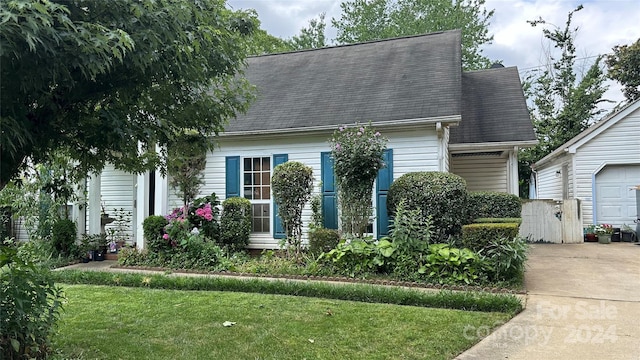 cape cod house with a front yard and a garage