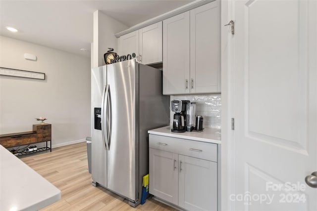 kitchen featuring decorative backsplash, stainless steel fridge, and light wood-type flooring