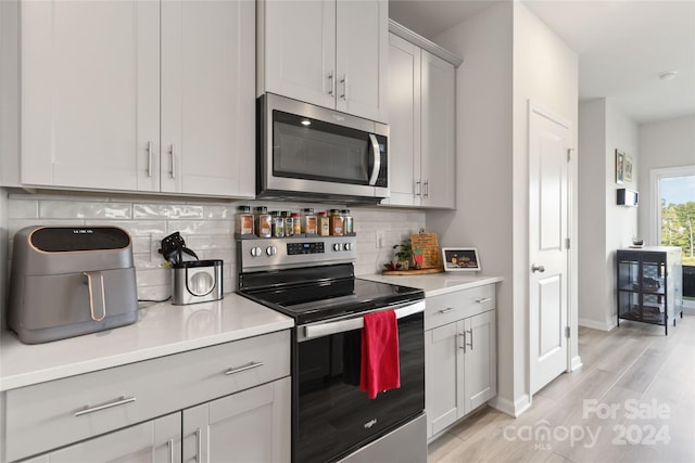 kitchen with stainless steel appliances, light hardwood / wood-style floors, and decorative backsplash