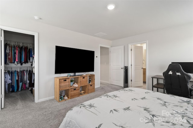 carpeted bedroom featuring a closet, connected bathroom, and a walk in closet