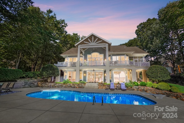 pool at dusk with a patio area