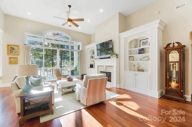 living room featuring a high end fireplace, hardwood / wood-style flooring, and ceiling fan