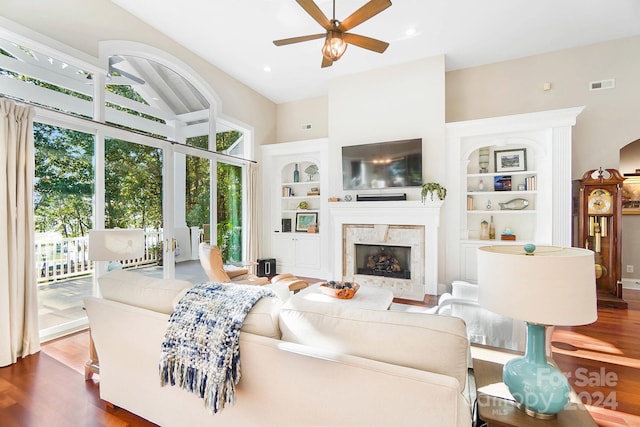 living room featuring a premium fireplace, ceiling fan, a high ceiling, and dark hardwood / wood-style flooring