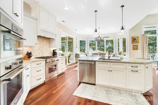 kitchen featuring dark wood-type flooring, decorative light fixtures, light stone counters, stainless steel appliances, and white cabinetry