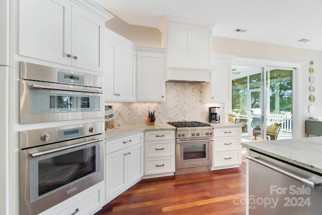 kitchen featuring tasteful backsplash, dark wood-type flooring, light stone counters, stainless steel appliances, and white cabinetry