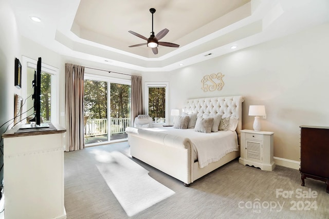 carpeted bedroom featuring ceiling fan, a tray ceiling, and access to outside