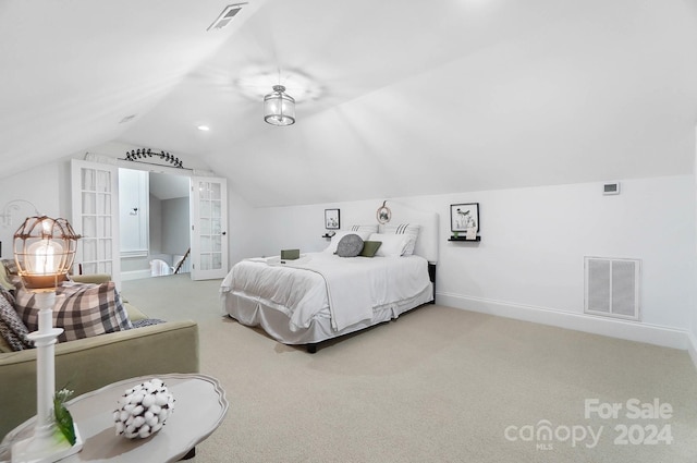 carpeted bedroom with vaulted ceiling and french doors