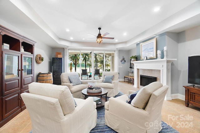 living room featuring ceiling fan, a tiled fireplace, and light tile patterned floors