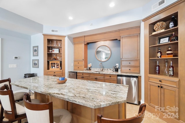 kitchen featuring light stone countertops, stainless steel fridge, a breakfast bar, and sink