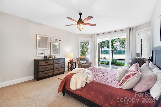 carpeted bedroom featuring ceiling fan and a water view