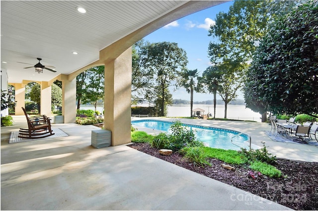 view of pool featuring ceiling fan, a water view, and a patio area