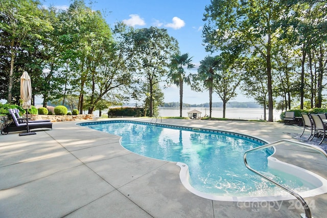 view of pool featuring a water view and a patio area