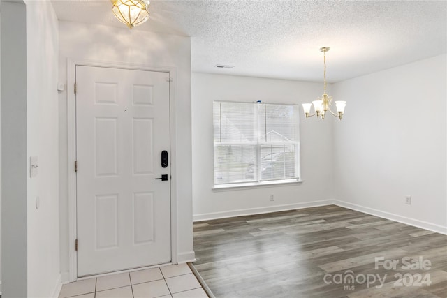 entrance foyer featuring a textured ceiling, an inviting chandelier, and hardwood / wood-style floors