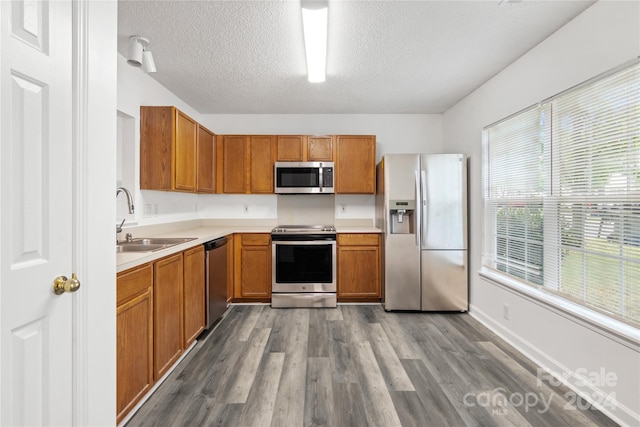 kitchen featuring light hardwood / wood-style floors, a textured ceiling, stainless steel appliances, and sink