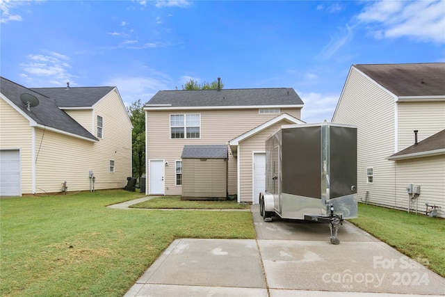 back of property with a storage unit, a garage, and a lawn