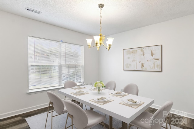 dining room with an inviting chandelier, dark hardwood / wood-style floors, and a textured ceiling