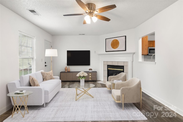 living room with ceiling fan, a textured ceiling, a fireplace, and hardwood / wood-style floors