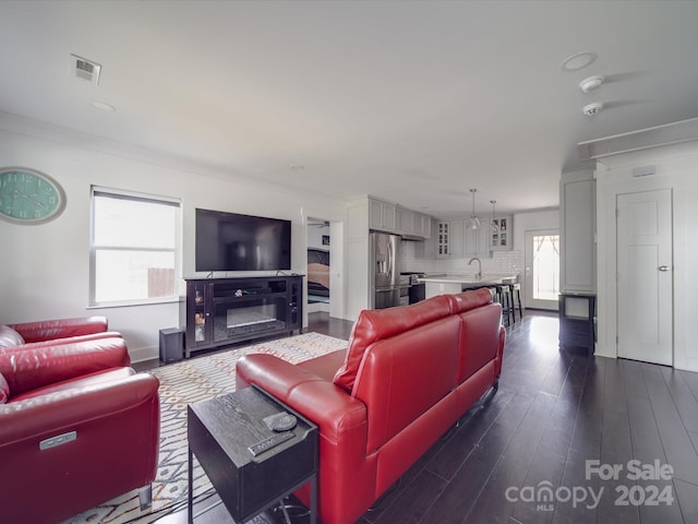 living room with ornamental molding, a healthy amount of sunlight, dark wood-type flooring, and sink