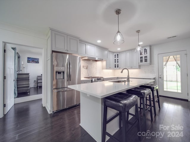 kitchen with sink, decorative light fixtures, a kitchen island with sink, dark wood-type flooring, and stainless steel appliances