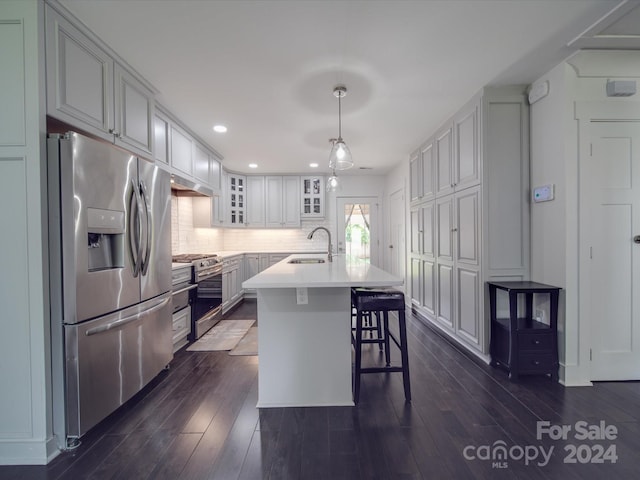 kitchen with sink, decorative light fixtures, a center island with sink, dark wood-type flooring, and appliances with stainless steel finishes