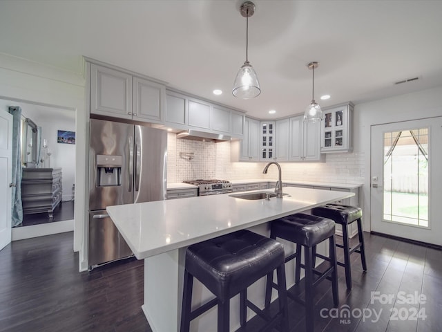 kitchen with hanging light fixtures, sink, a center island with sink, dark wood-type flooring, and appliances with stainless steel finishes