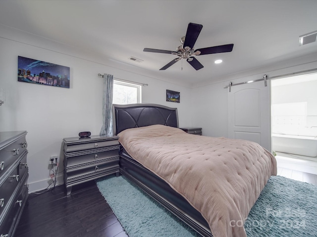 bedroom featuring a barn door, ceiling fan, and dark wood-type flooring