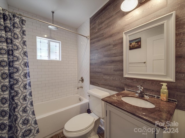 full bathroom featuring wooden walls, shower / bathtub combination with curtain, vanity, and toilet