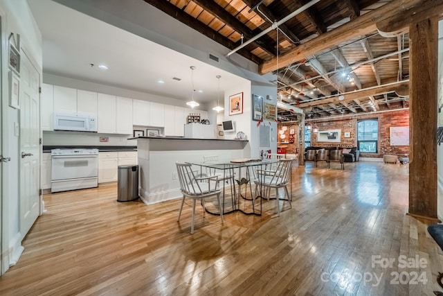 kitchen with light wood-type flooring, white cabinetry, a kitchen bar, white appliances, and brick wall