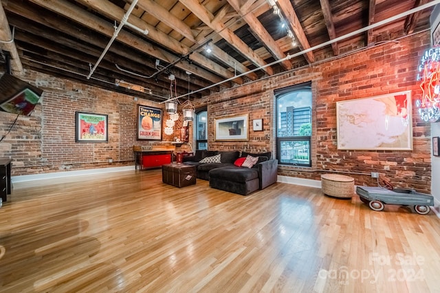 living room featuring brick wall, hardwood / wood-style flooring, and rail lighting