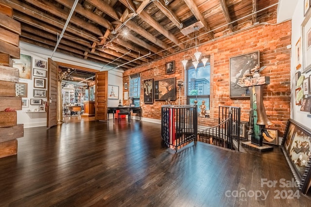 misc room featuring brick wall, beam ceiling, and dark wood-type flooring