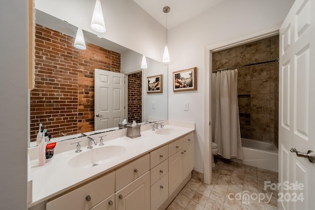 full bathroom featuring brick wall, vanity, toilet, and shower / tub combo with curtain