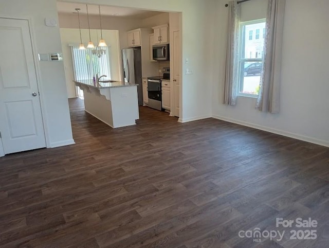 kitchen with white cabinetry, a kitchen breakfast bar, decorative light fixtures, a kitchen island with sink, and appliances with stainless steel finishes